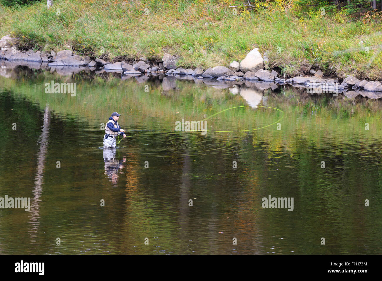Man fly fishing in a river in upstate New York in Adirondacks State