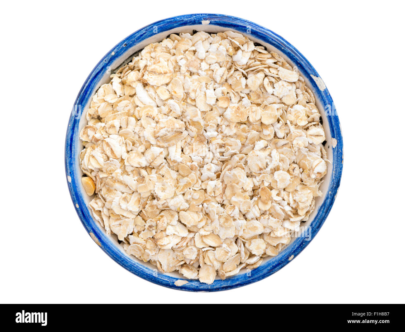 many oat flakes in small blue cup isolated on white Stock Photo