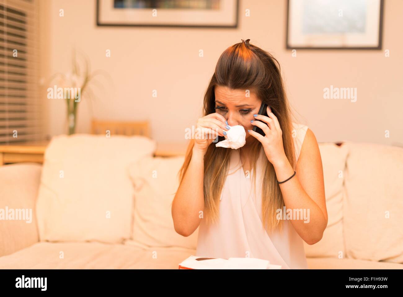 Young woman having telephone conversation, crying Stock Photo