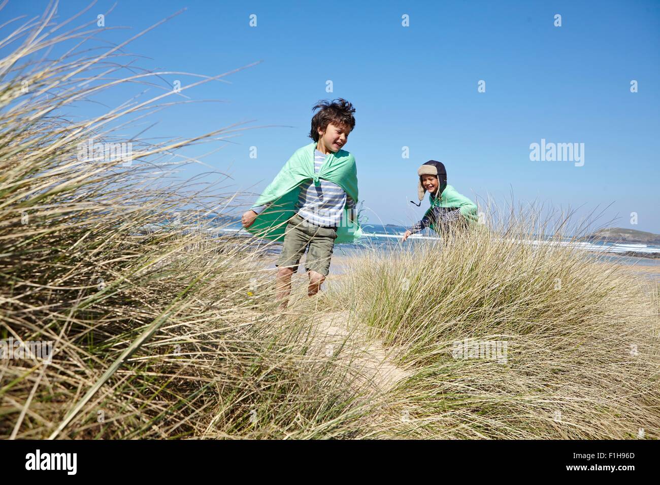 Two young boys, wearing fancy dress, playing on beach Stock Photo