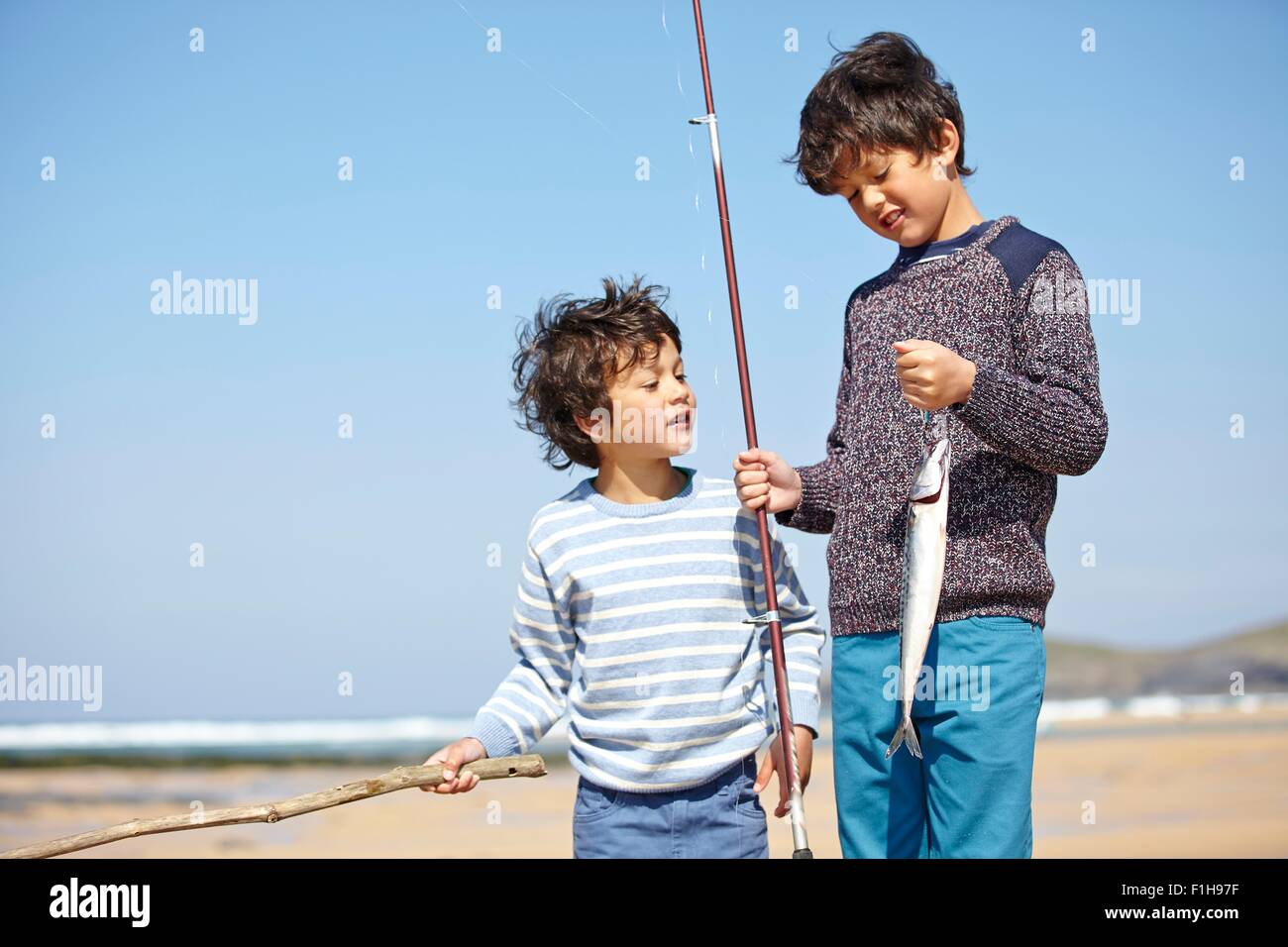 Two young boys standing together, holding fishing rod and fish Stock Photo