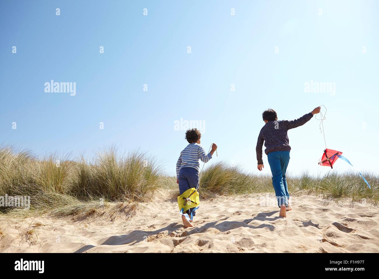 Two young boys, flying kites on beach Stock Photo