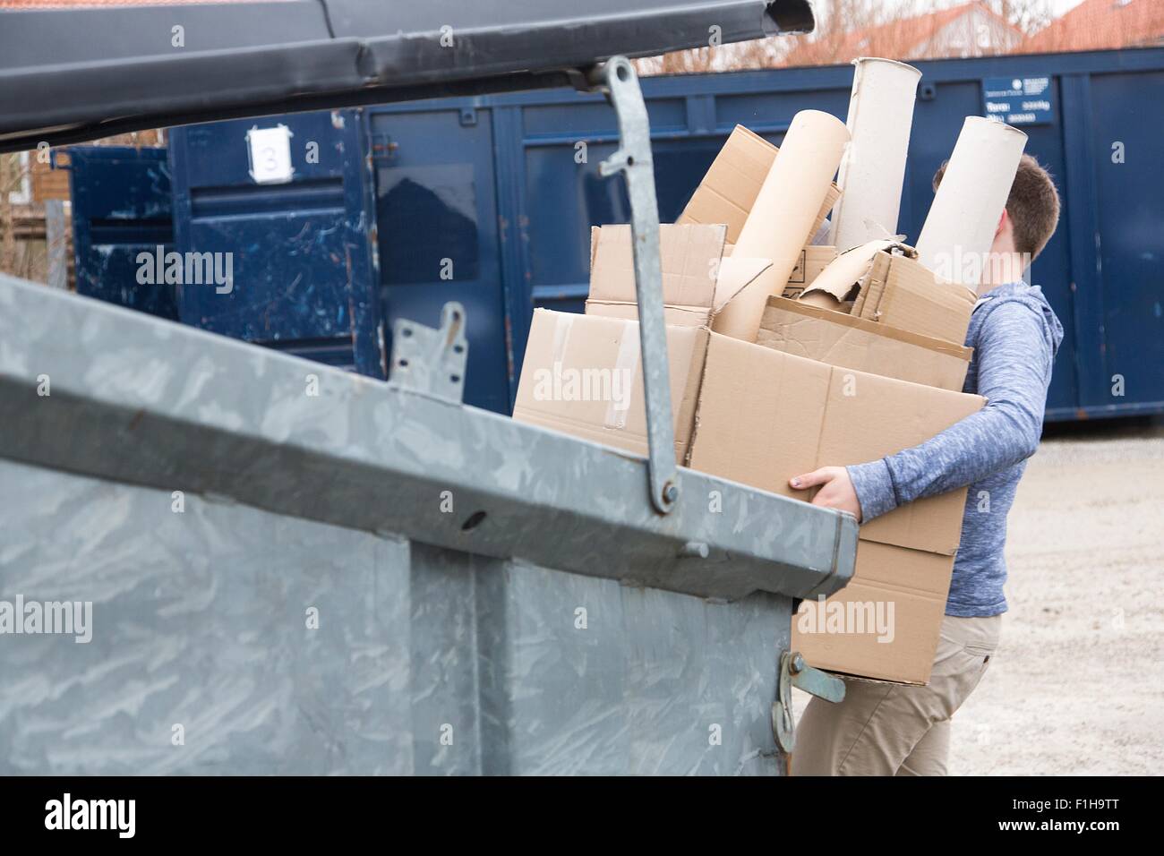 Teenage boy carrying cardboard waste to recycling bin Stock Photo