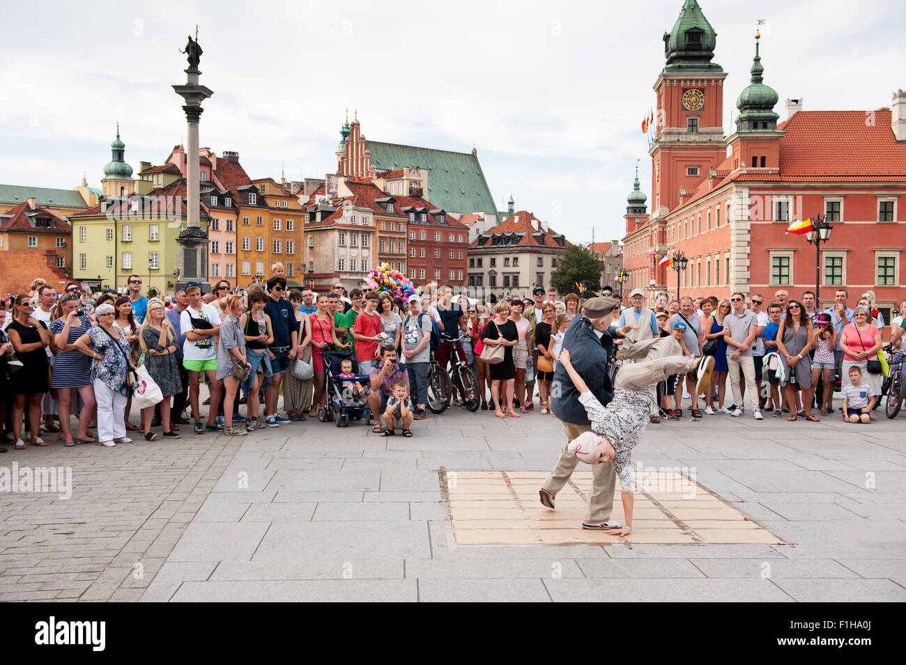 Oldie breakdance show, tourists watching street dance performance in Old Town square in Warsaw, Poland. Old couple in masks. Stock Photo