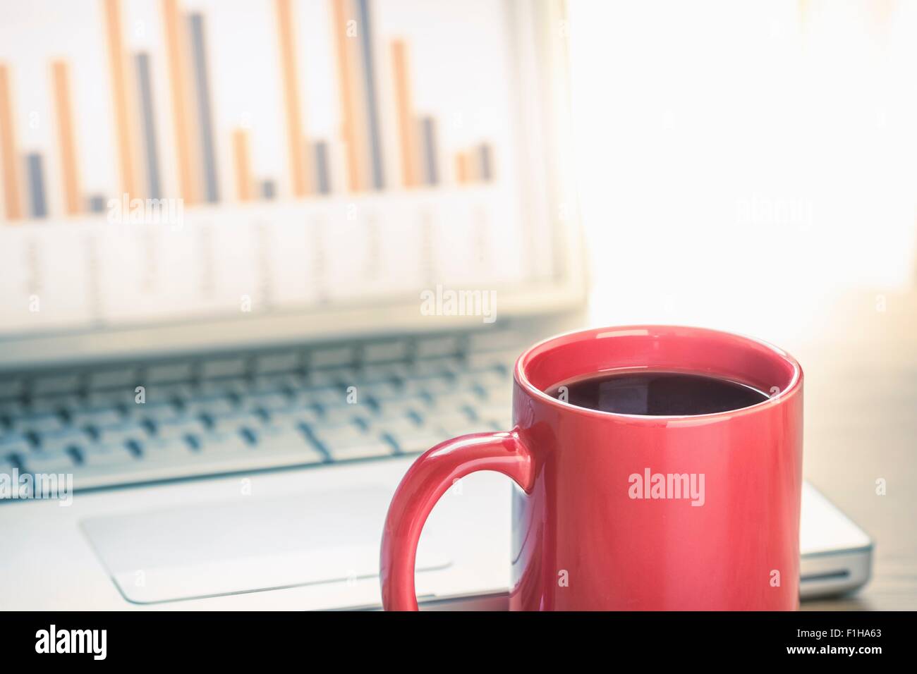 Close up still life of black coffee and bar finance chart on laptop screen Stock Photo