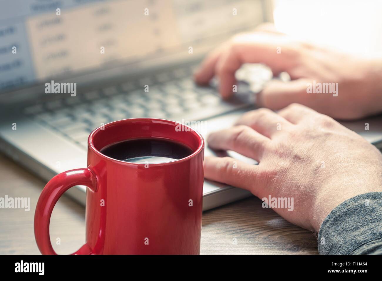 Hands of man typing on laptop at desk Stock Photo