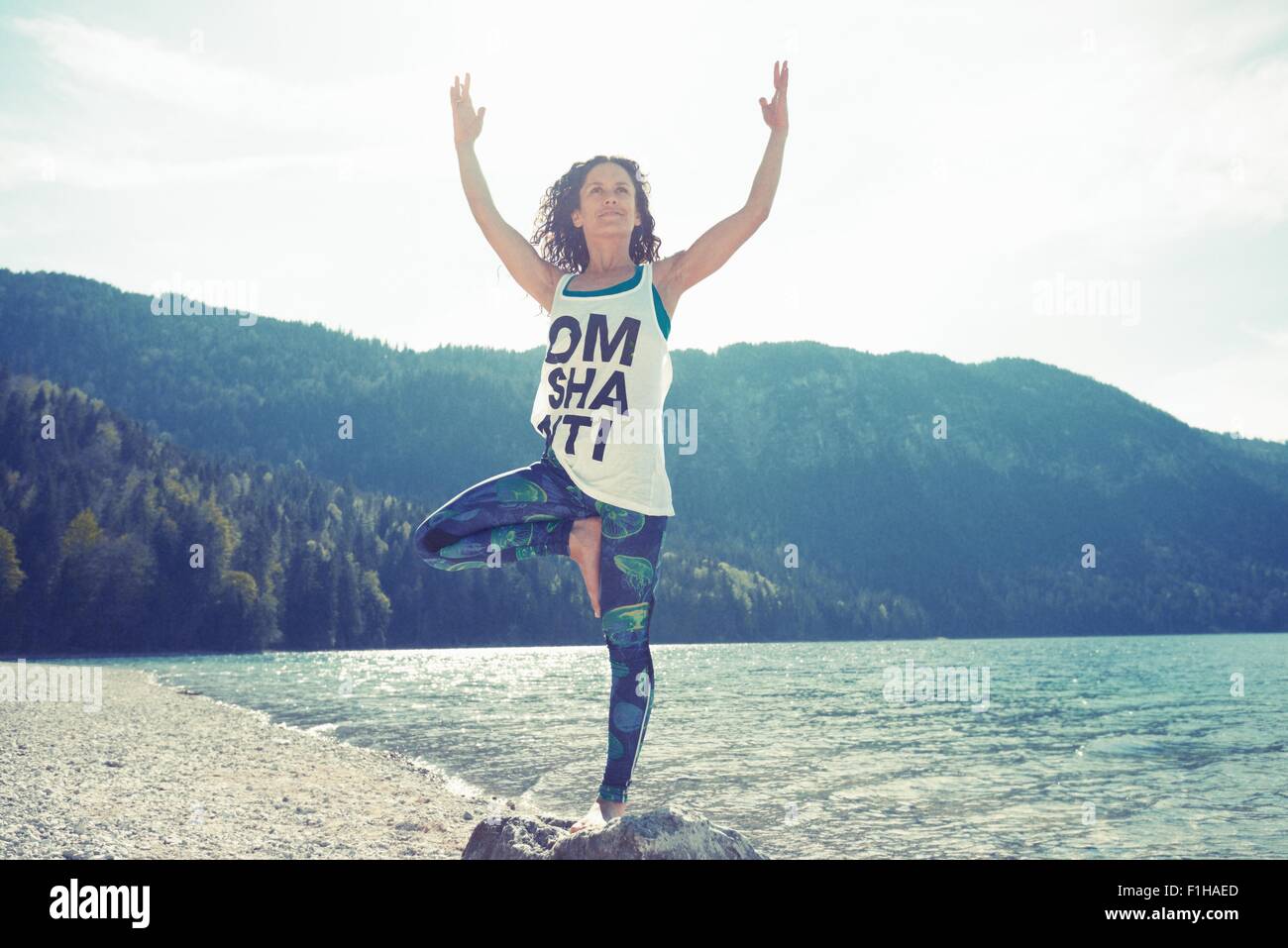 Mid adult woman, standing on rock, in yoga position Stock Photo