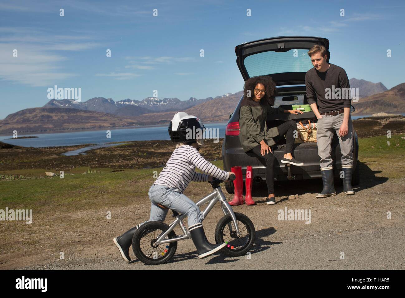 Parents watching son ride bike, Loch Eishort, Isle of Skye, Hebrides, Scotland Stock Photo
