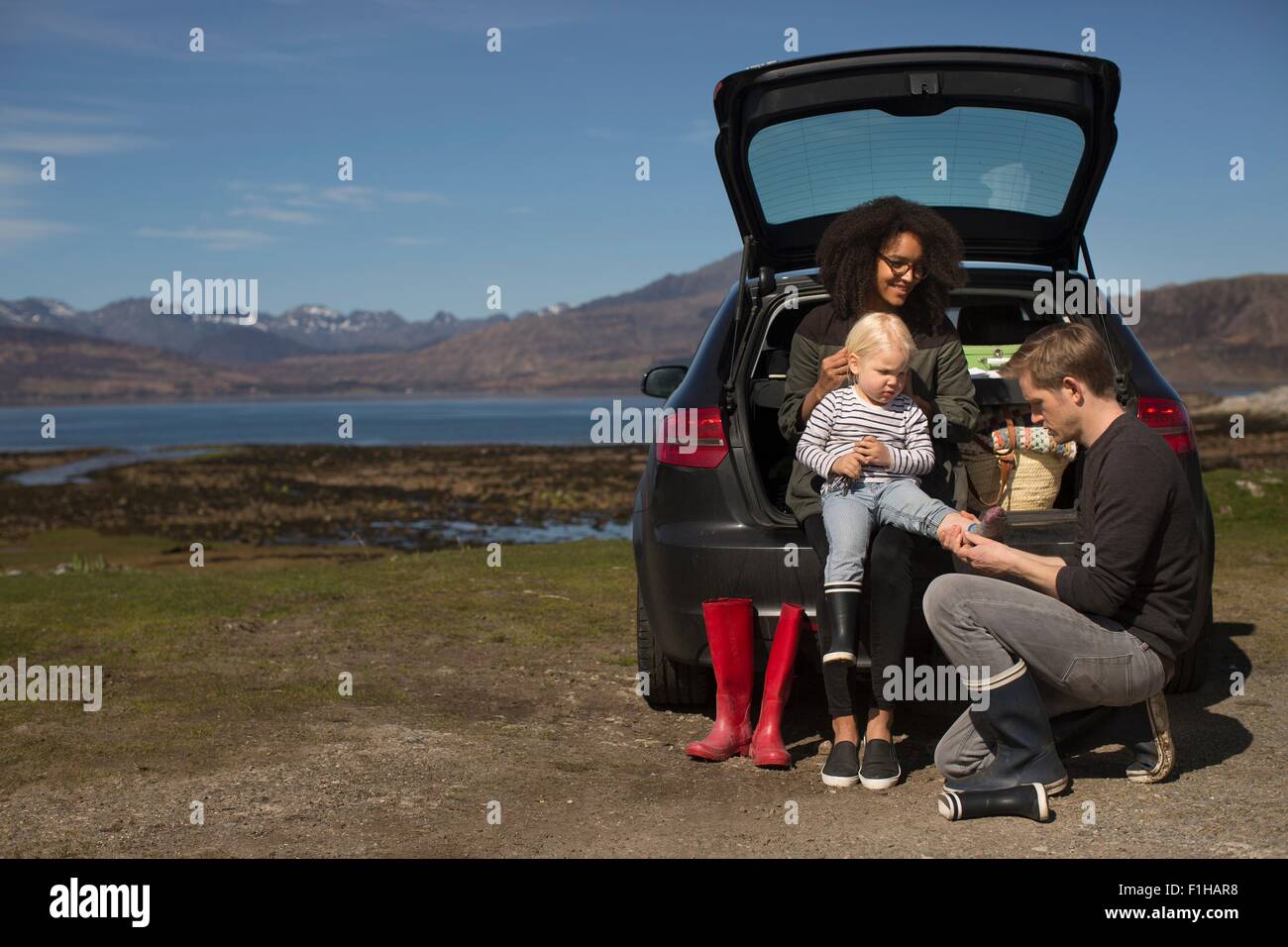 Parents helping son change shoes, Loch Eishort, Isle of Skye, Hebrides, Scotland Stock Photo