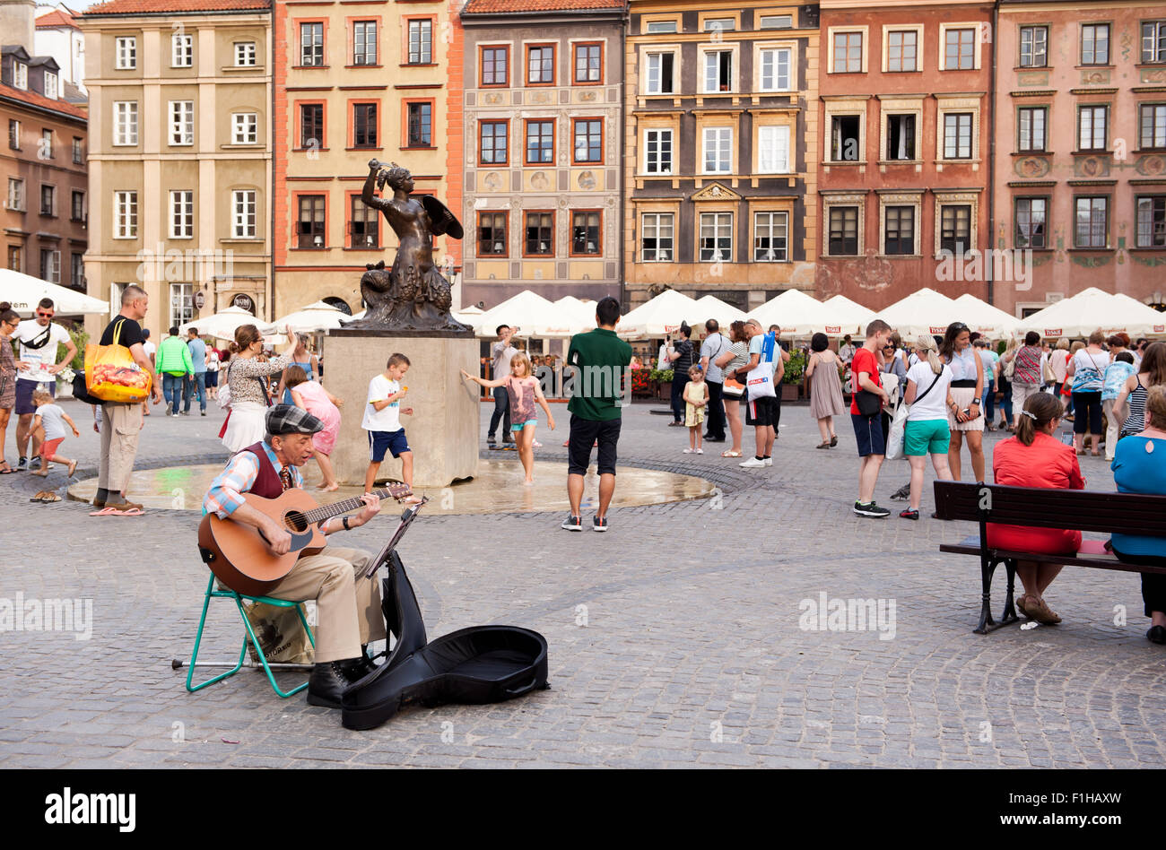 Old man busker gig playing guitar in Old Town Market Place square in Warsaw, Poland. Street art singer performer alone show. Stock Photo