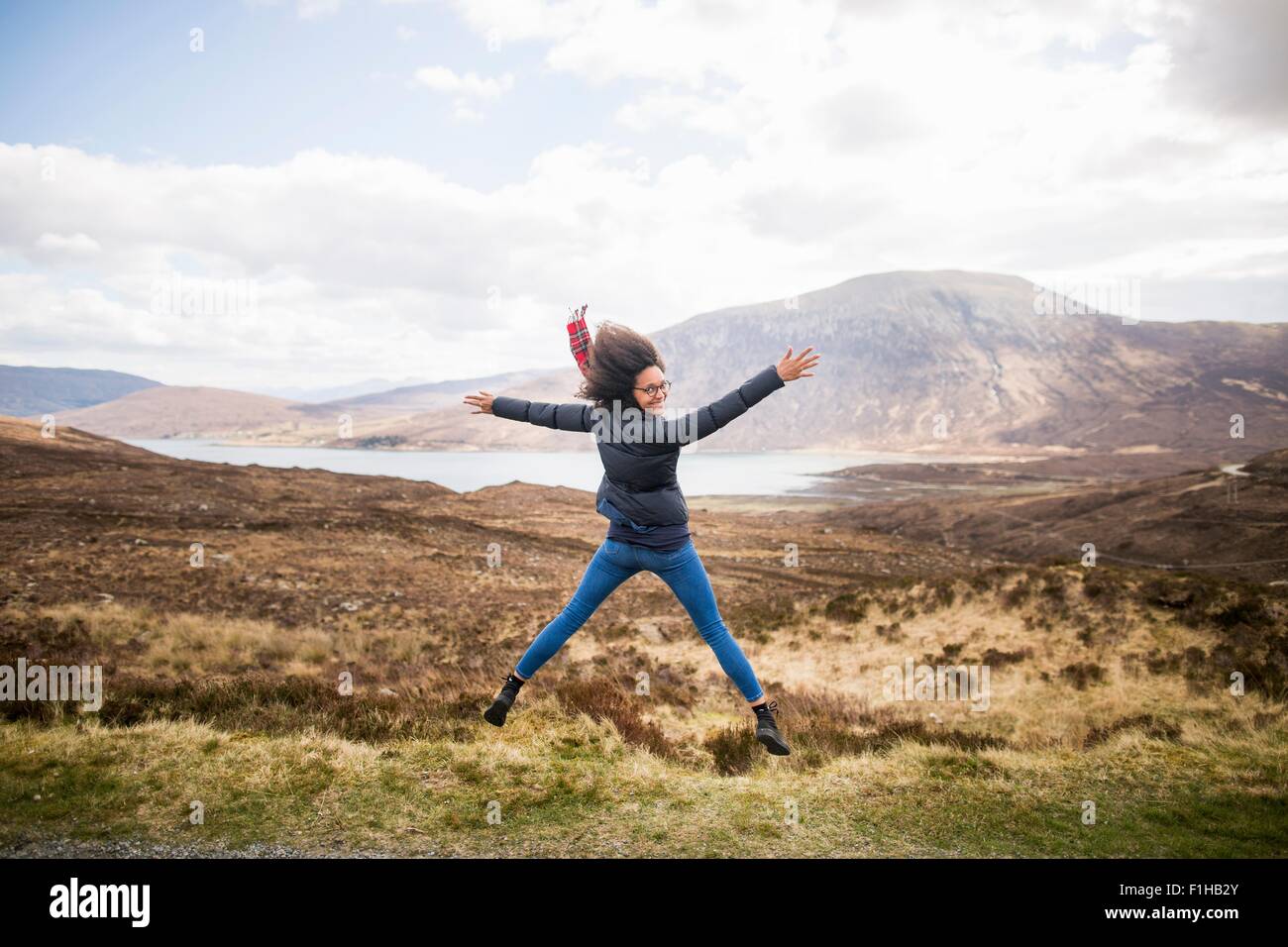Mid adult woman in mountains doing star jump, Isle of Skye, Hebrides, Scotland Stock Photo