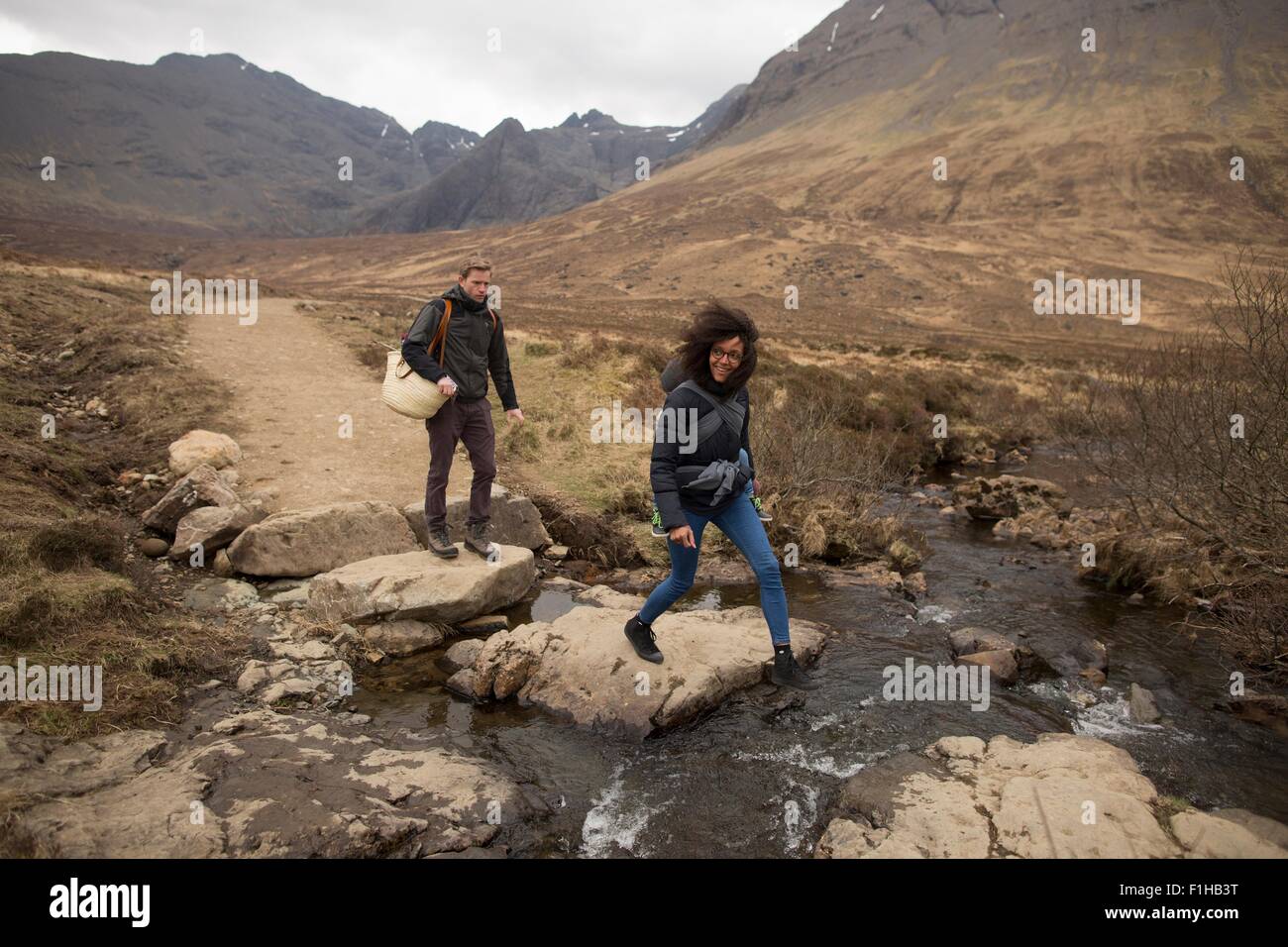 Woman crossing stream, Fairy Pools, near Glenbrittle, Isle of Skye, Hebrides, Scotland Stock Photo