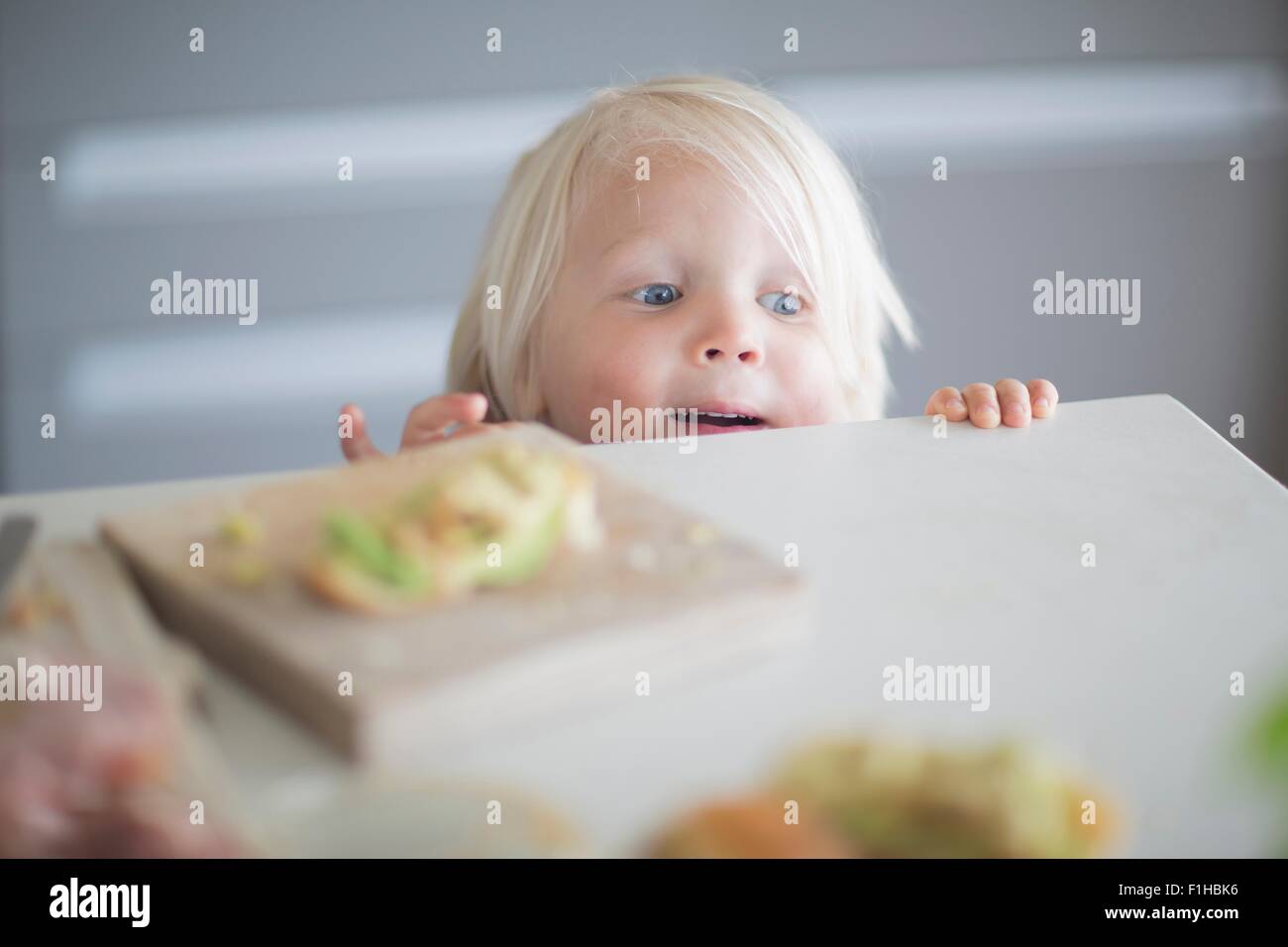 Boy peeking over kitchen counter Stock Photo