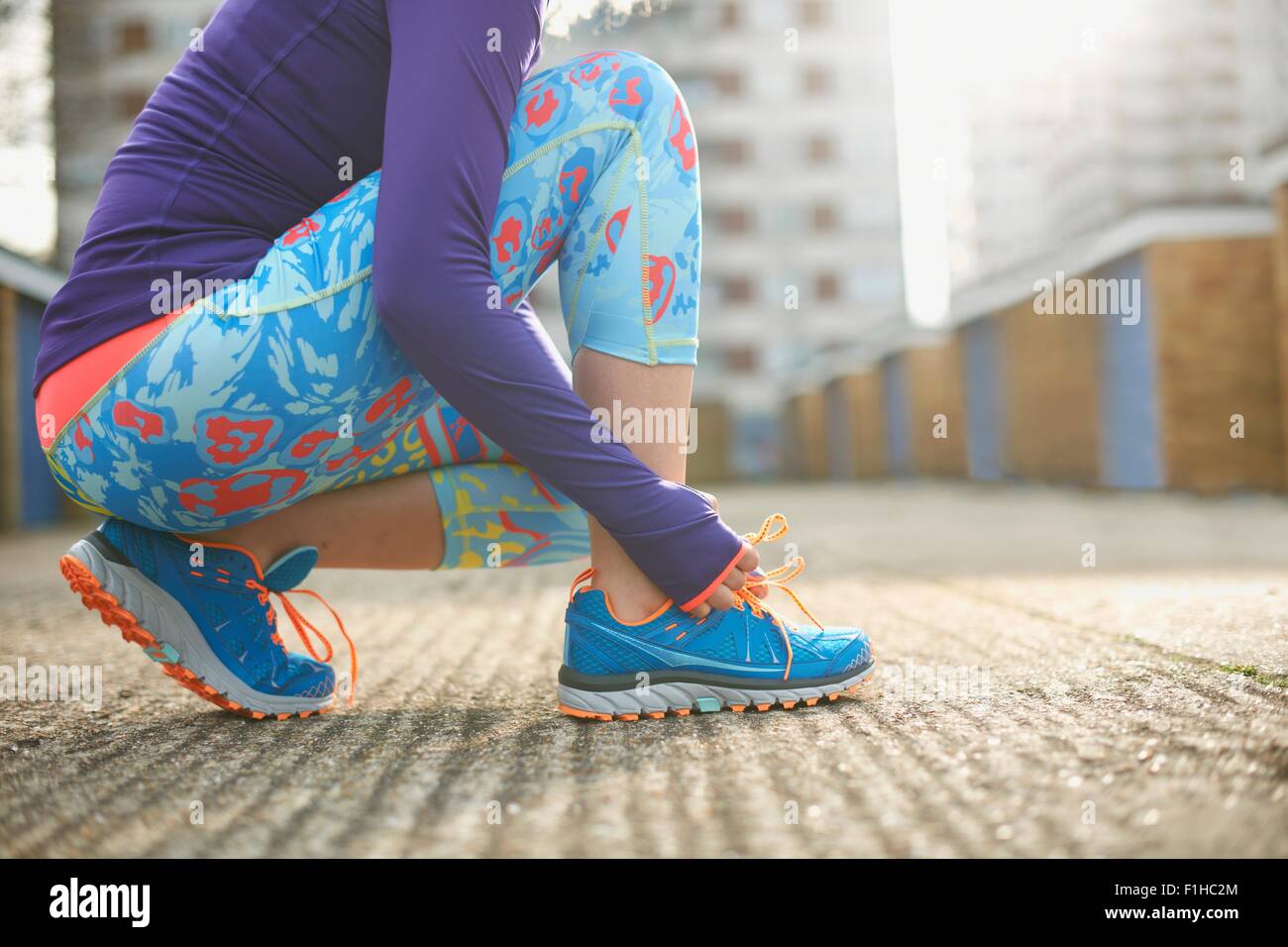 Cropped view of woman bending to tie sports training shoe lace Stock