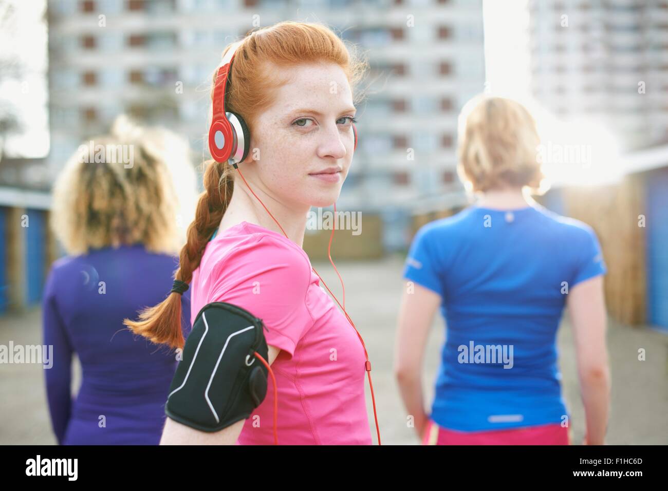 Portrait of woman wearing armband and headphones before exercise looking over shoulder at camera Stock Photo