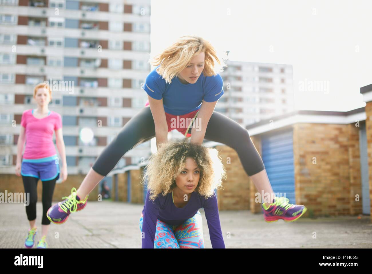 Three women exercising together wearing sports clothing and playing leap frog Stock Photo