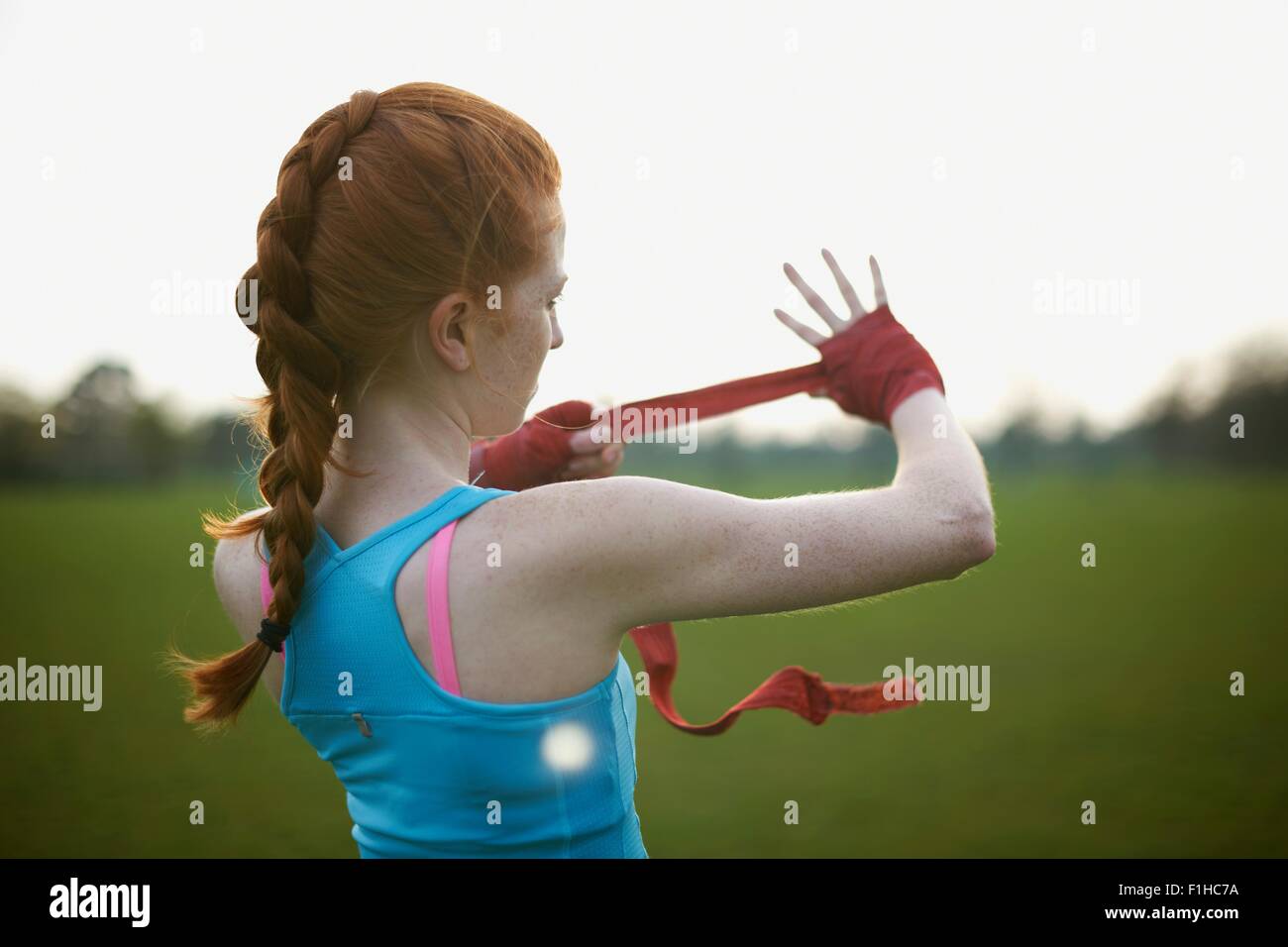 Portrait of a woman putting on boxing gloves straps in the park Stock Photo