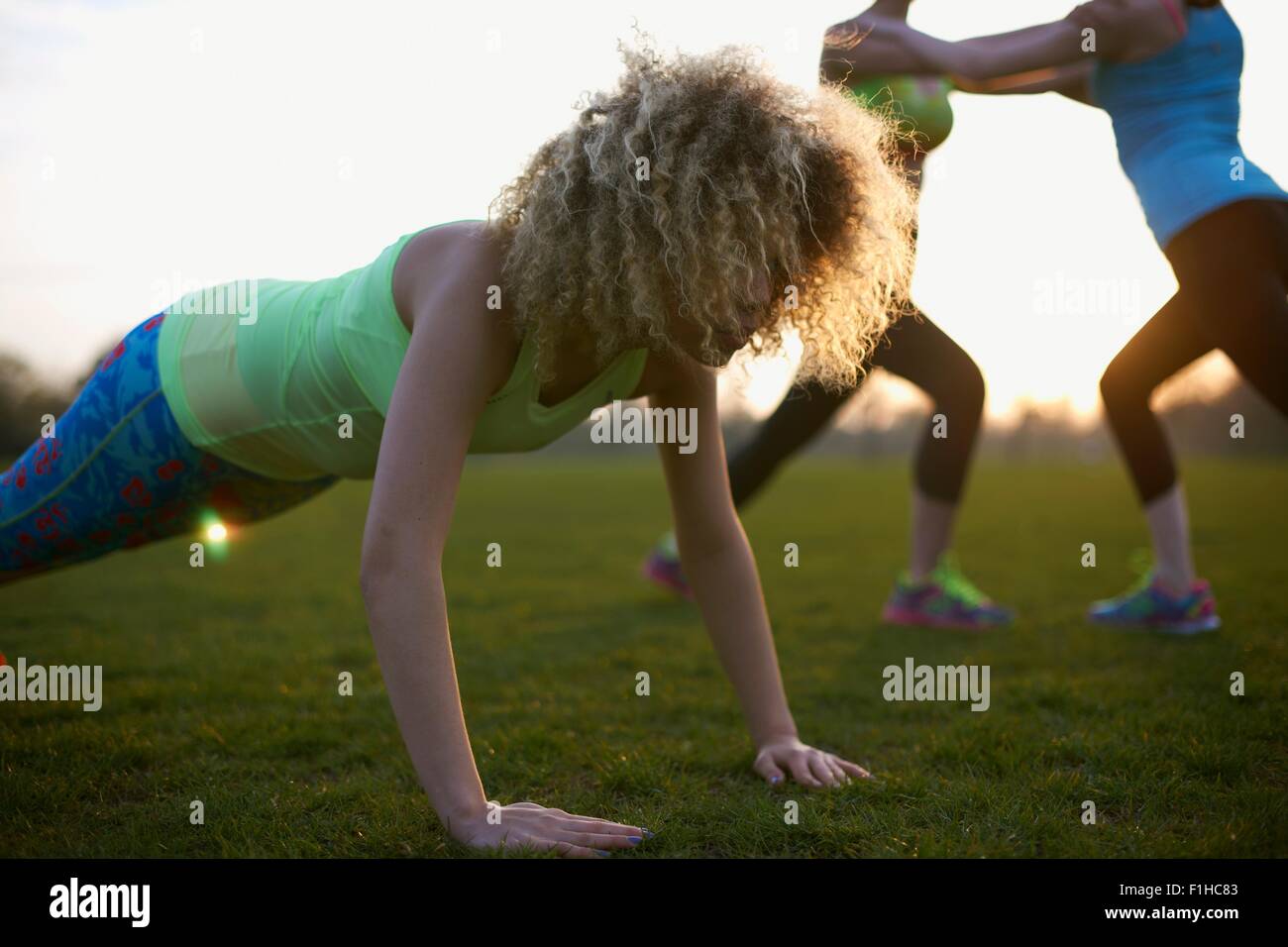 Portrait of woman doing push up exercise in park Stock Photo