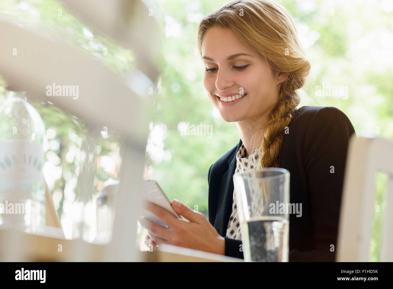 Young woman in cafe reading texts on smartphone Stock Photo