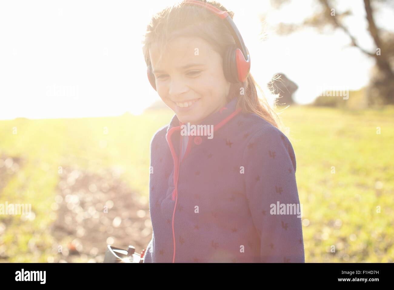 Smiling girl wearing headphones metal detecting  in field Stock Photo
