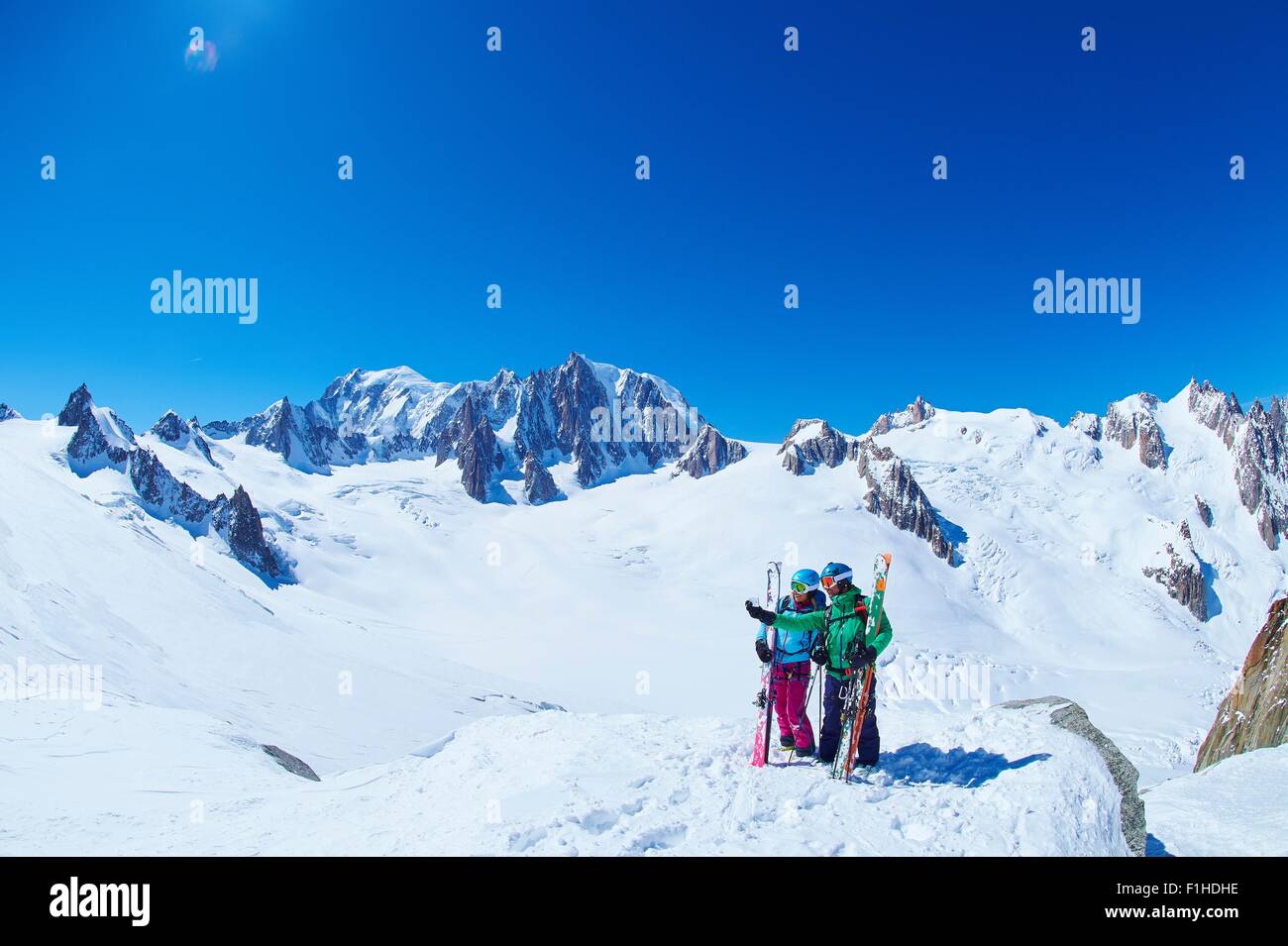Mature male and female skiers on ridge at Mont Blanc massif, Graian Alps, France Stock Photo