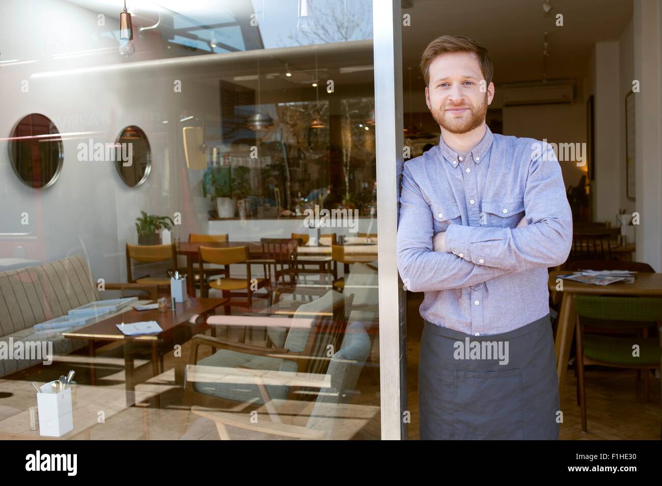 Portrait of young male cafe owner with arms folded in doorway Stock Photo