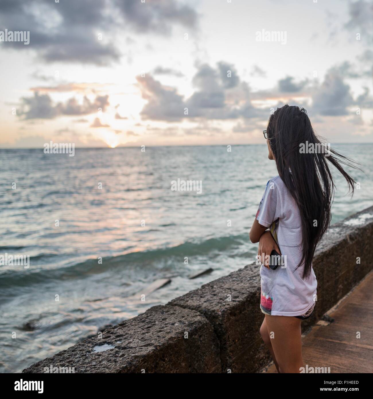 Young woman watching sunrise, Kaaawa beach, Oahu, Hawaii, USA Stock Photo