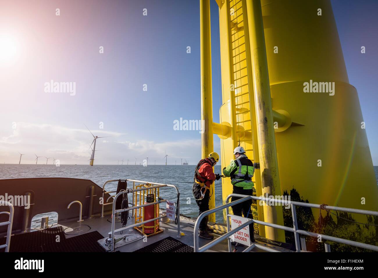 Engineers climbing wind turbine at offshore wind farm Stock Photo