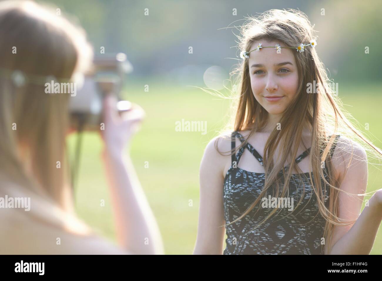 Teenage girl photographing best friend using instant camera in park Stock Photo