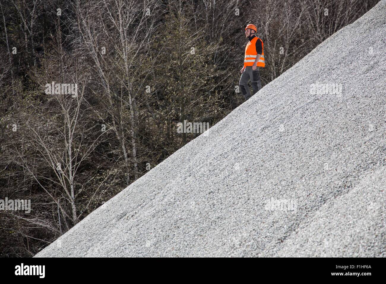 Quarry worker moving down gravel mound at quarry Stock Photo