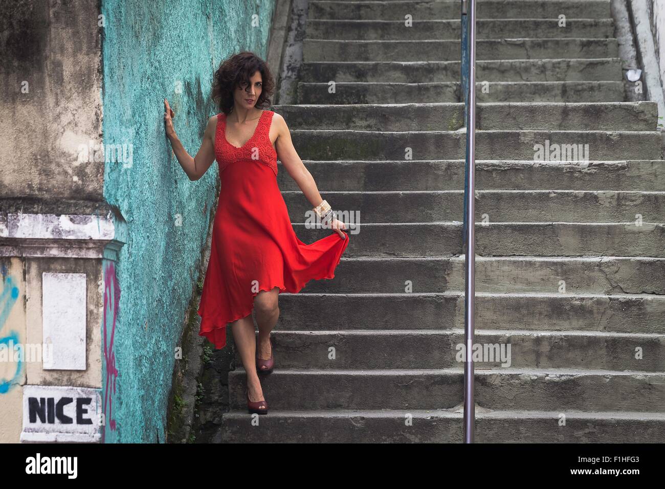 Fashion model wearing red dress walking down steps Stock Photo