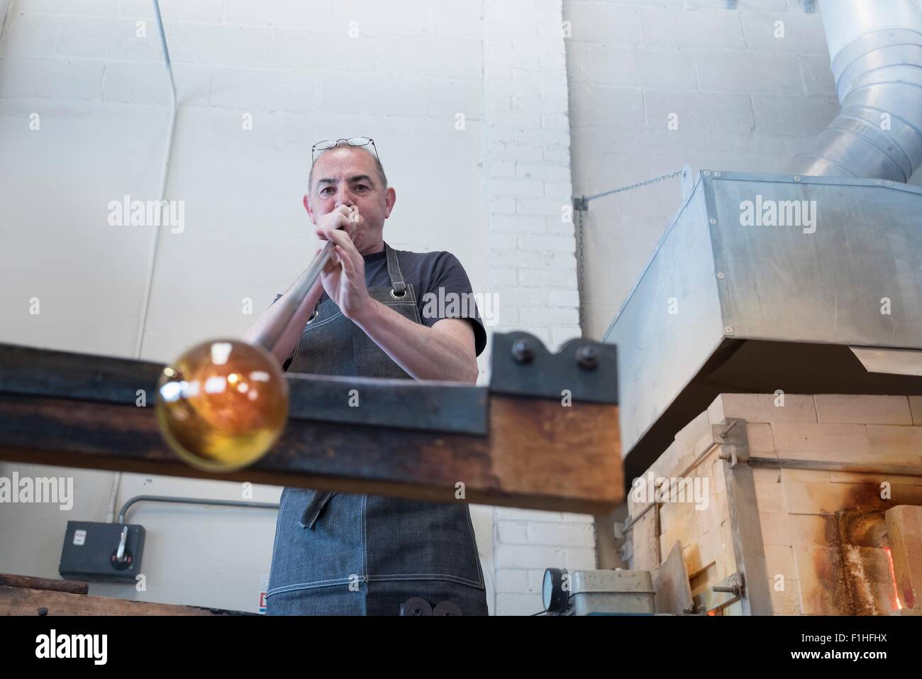 Glassblower blowing hot glass Stock Photo