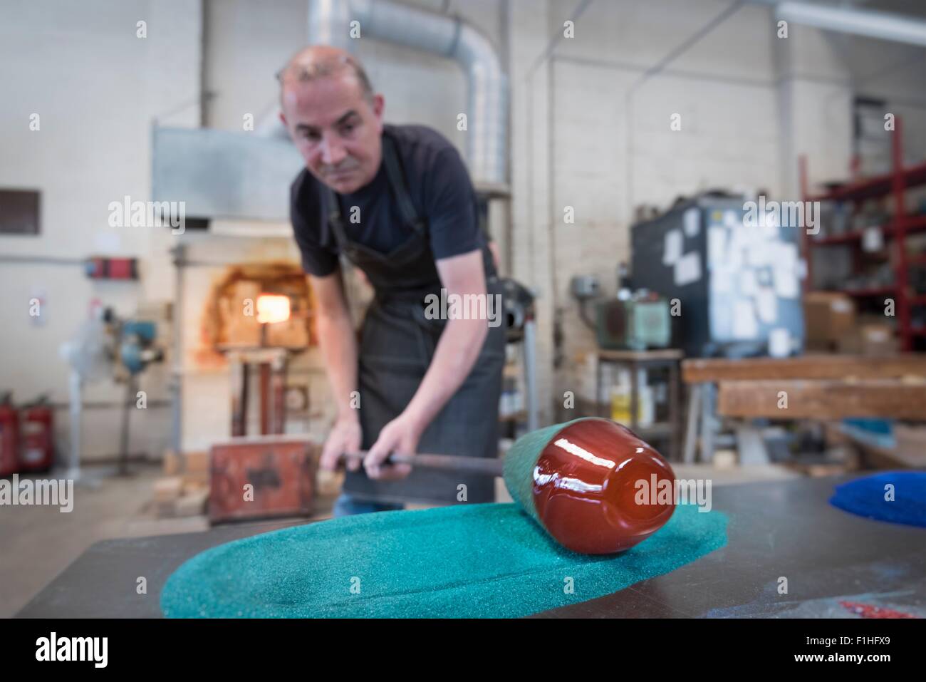 Glassblower adding colour to hot glass Stock Photo