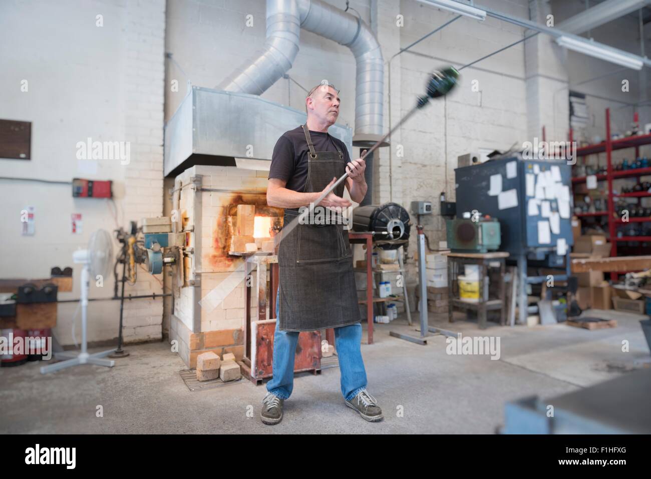 Glassblower spinning hot glass Stock Photo