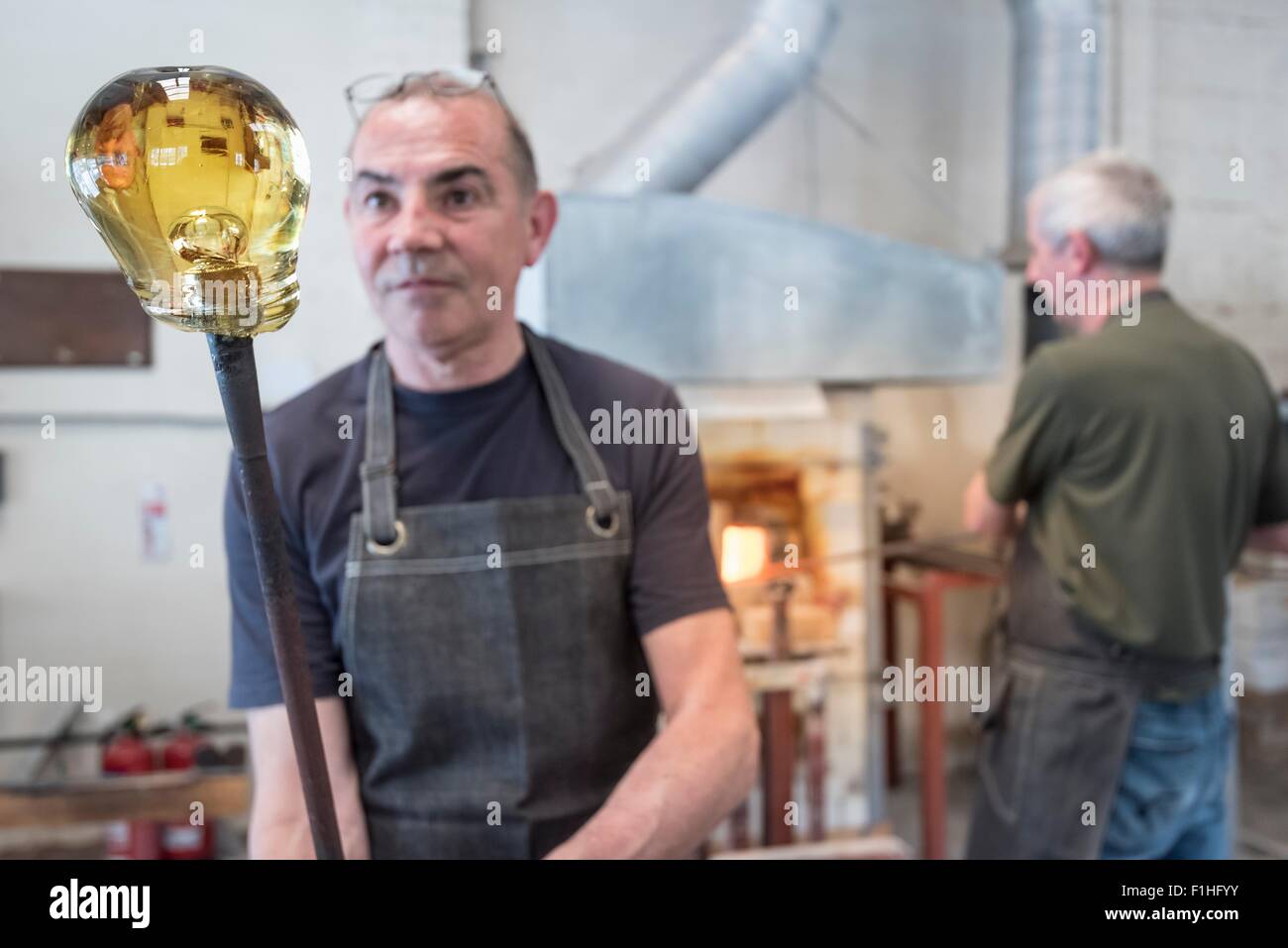 Glassblower with large blob of hot glass Stock Photo