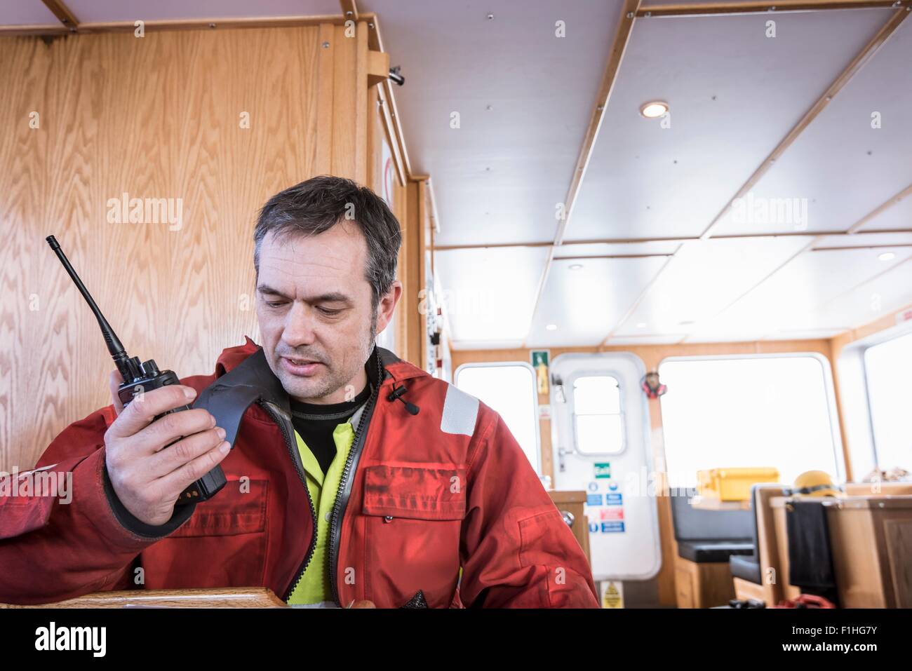 Engineer on boat speaking on walkie talkie to engineers on wind turbine