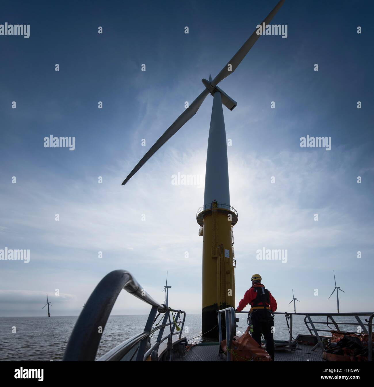 Engineer preparing to climb windturbine at offshore windfarm Stock Photo