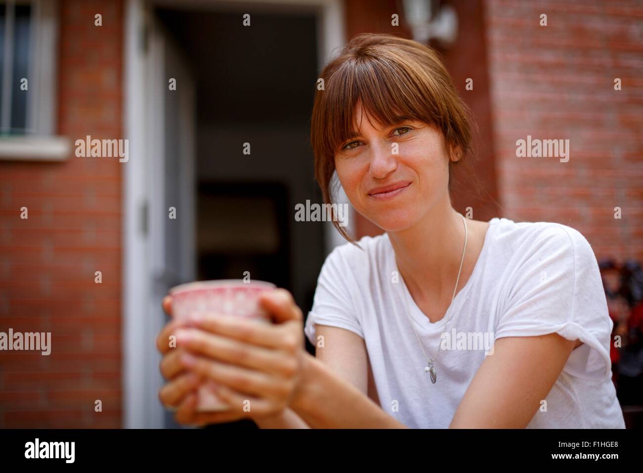 Mid adult woman sitting smelling lavender, smiling at camera Stock Photo