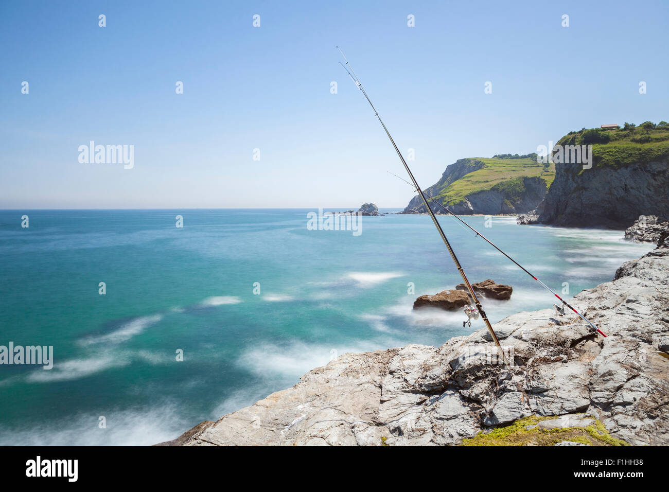 Fishing rods stand up on a rocky coast over the sea Stock Photo