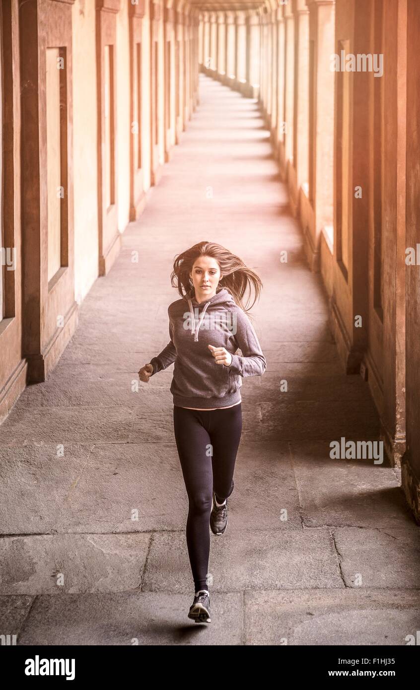 Front view of young woman wearing sports clothes jogging Stock Photo