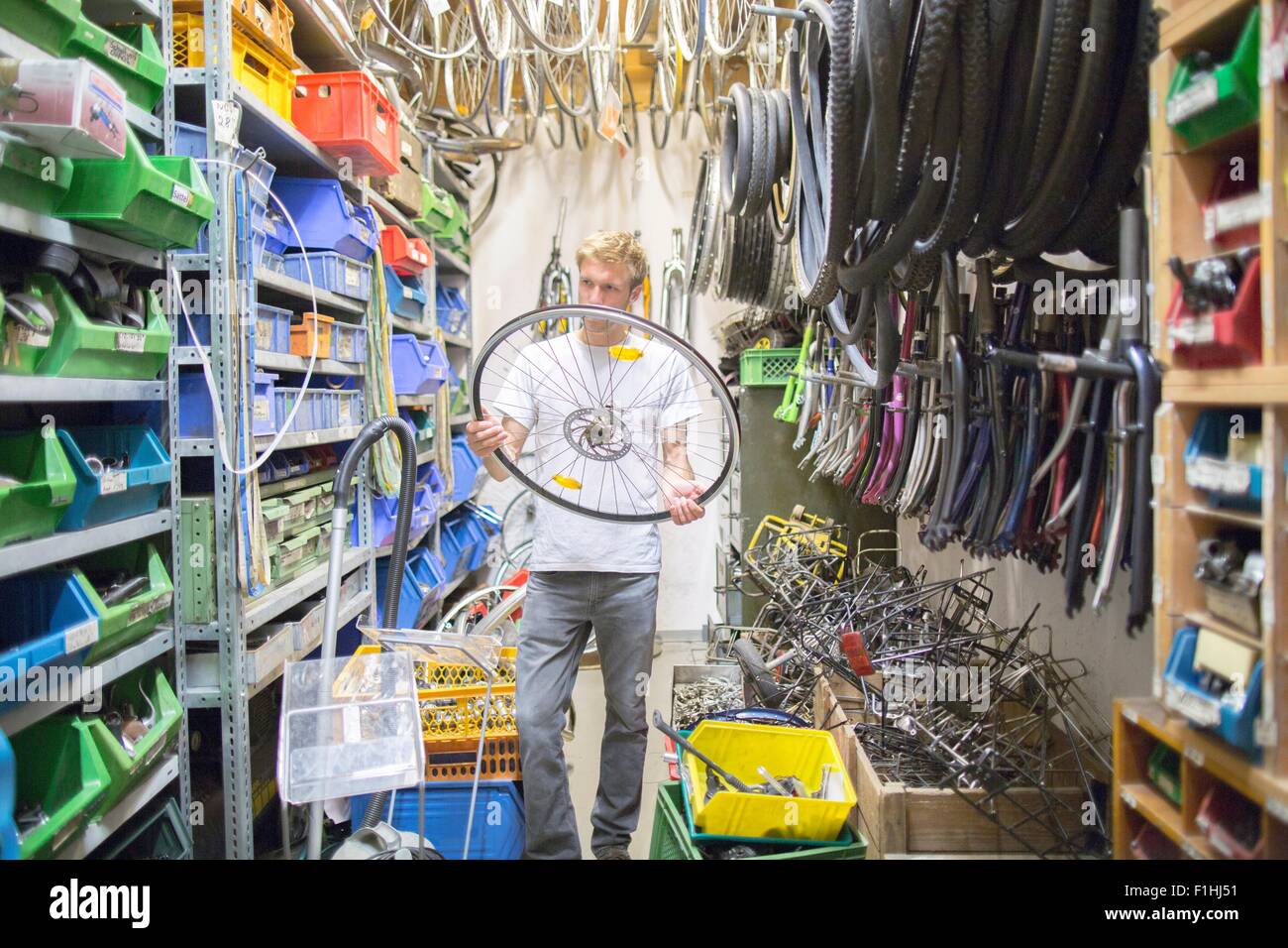 Mid adult man in storage room holding bicycle wheel Stock Photo