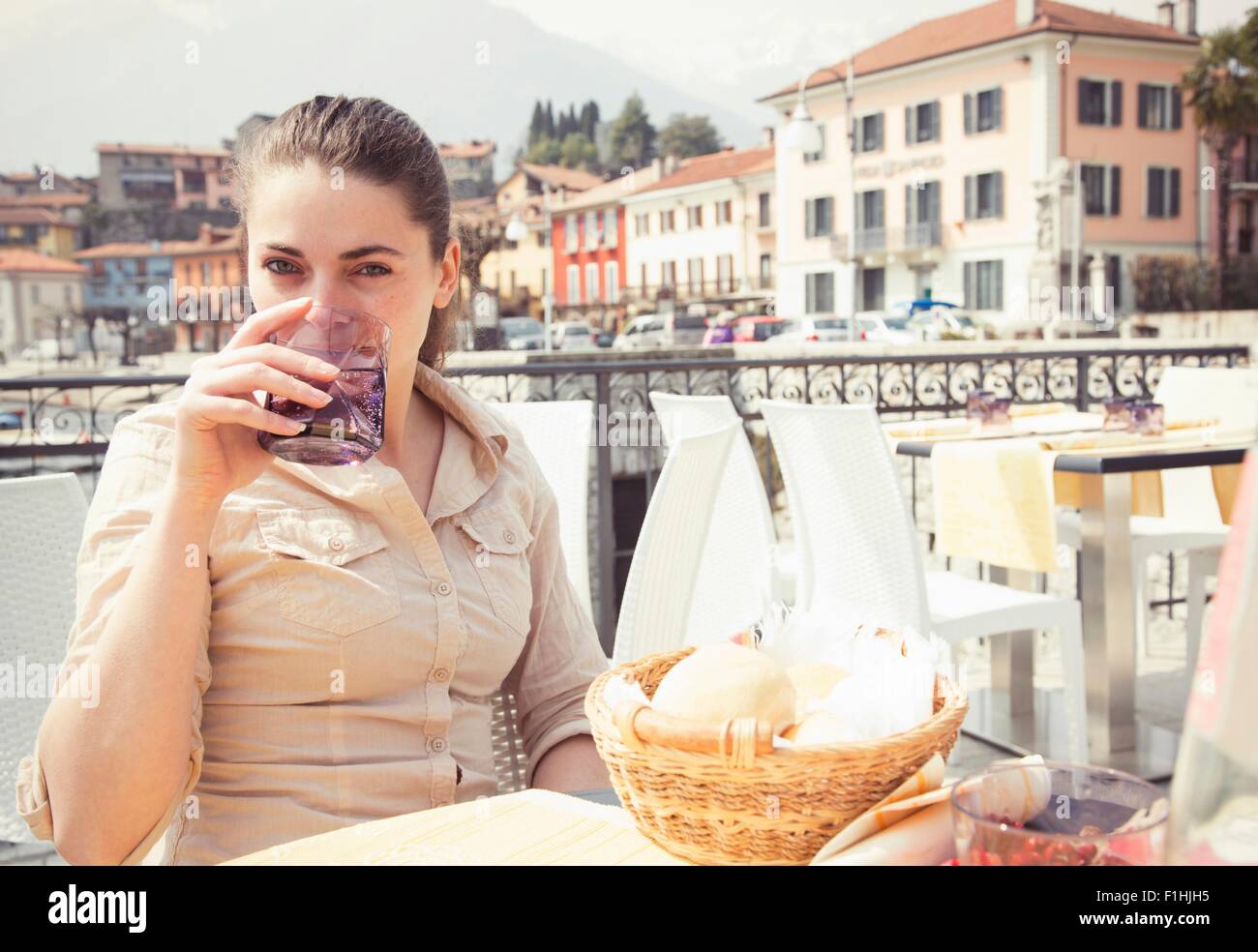 Portrait of young woman drinking water at lakeside restaurant, Lake Mergozzo, Verbania, Piemonte, Italy Stock Photo
