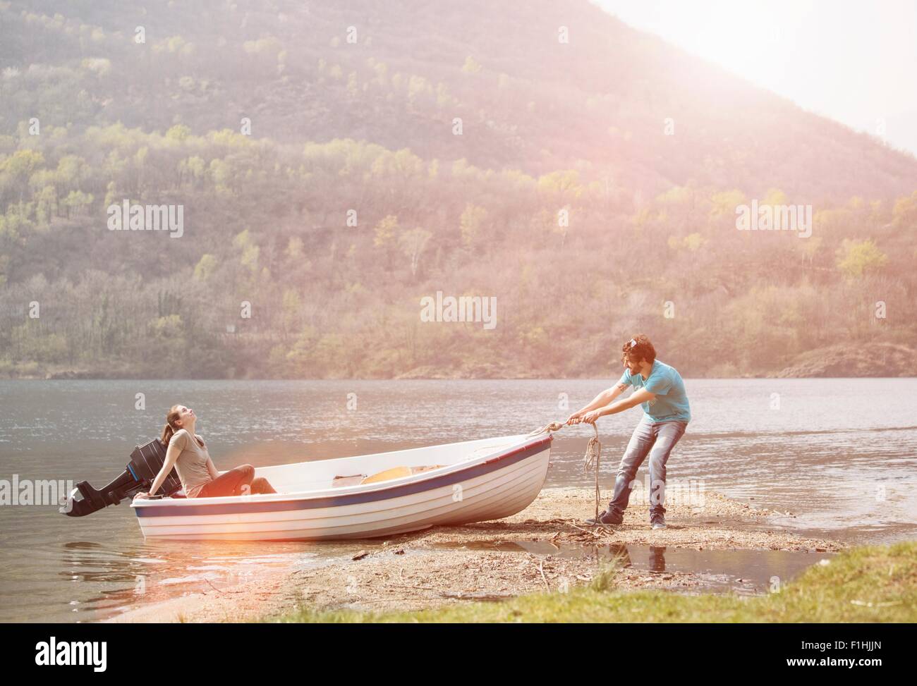 Young man pulling girlfriend in boat, Lake Mergozzo, Verbania, Piemonte, Italy Stock Photo