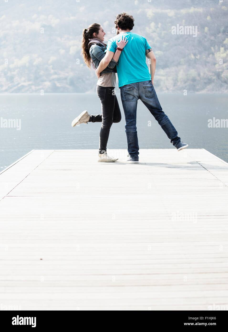 Young couple standing on one leg on pier at Lake Mergozzo, Verbania, Piemonte, Italy Stock Photo