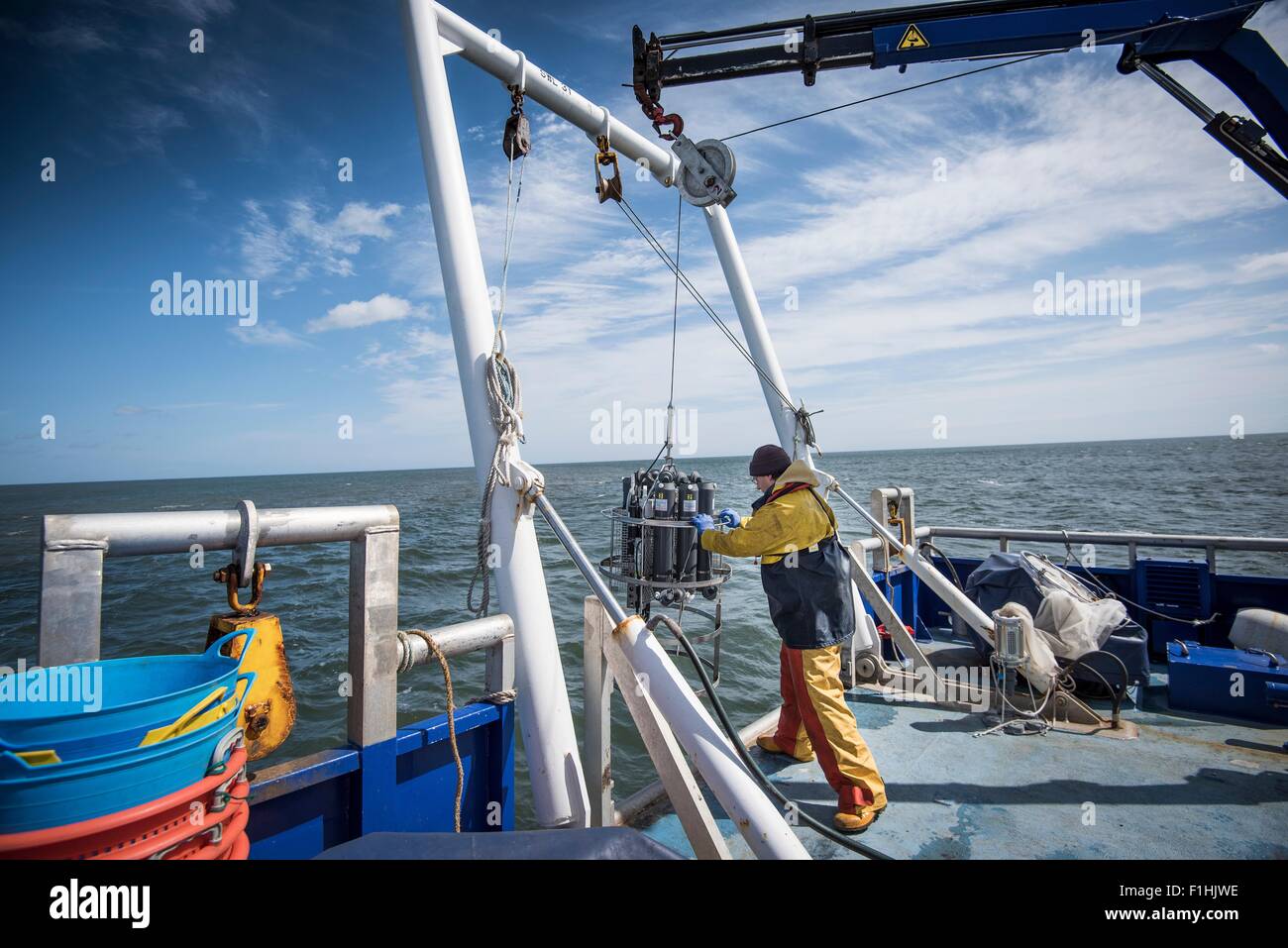 Scientist lowering sea water sampling experiment into sea on research ship Stock Photo
