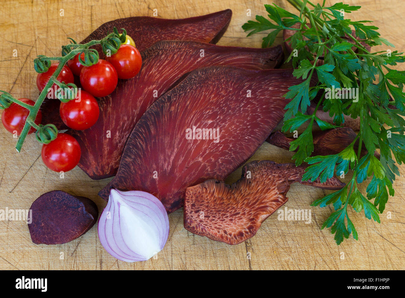 Pick wood with slices of liver Fistula Needles(fistulina hepatica or Beefsteak Fungus ), red onion, cherry tomatoes and parsley Stock Photo