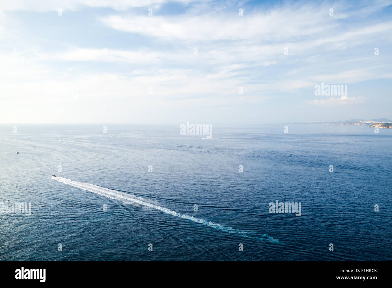 Mediterranean sea landscape with wake of small fast motorboat under blue cloudy sky Stock Photo