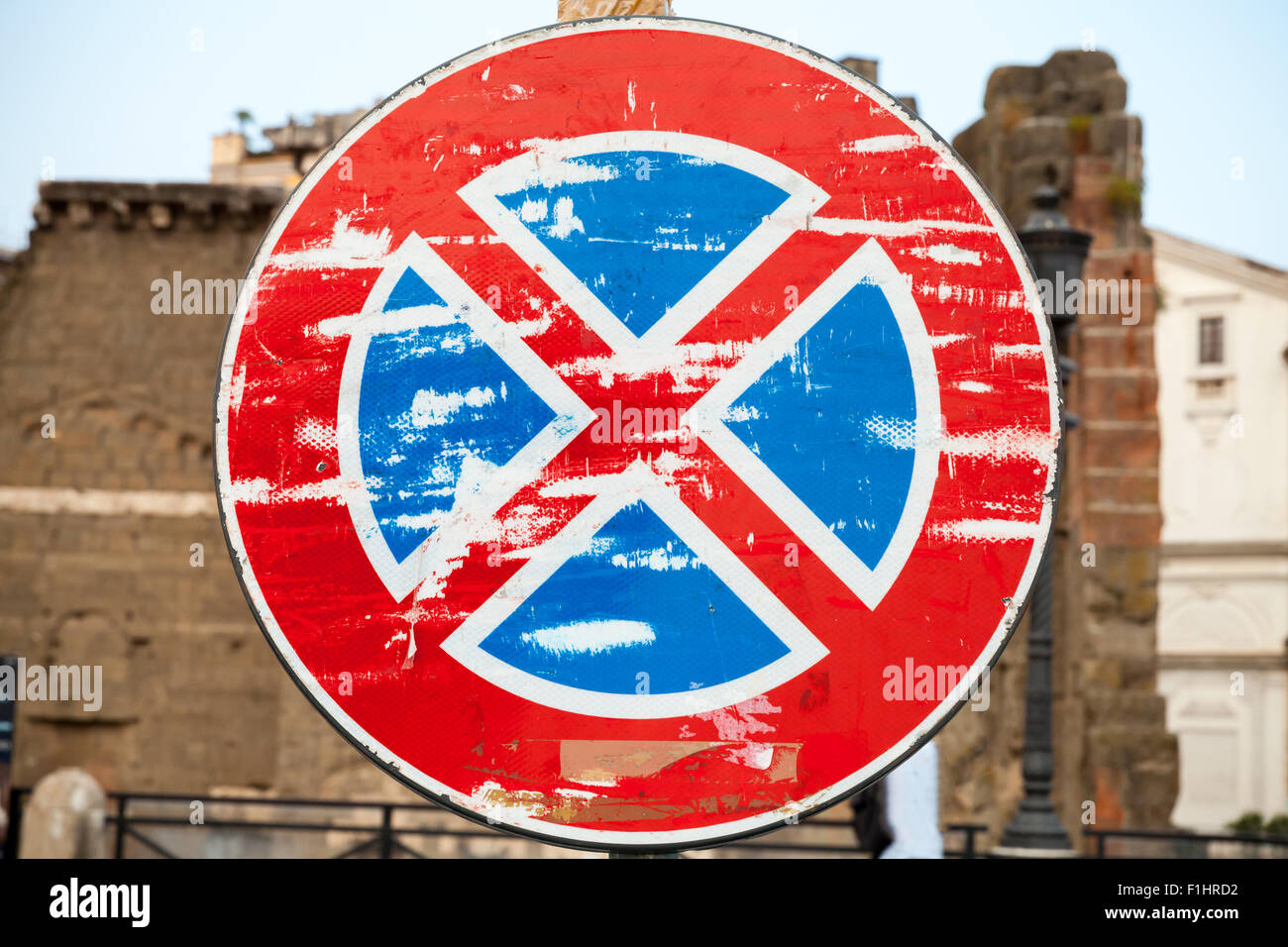 Round grungy road sign against old blurred city background, standing is prohibited Stock Photo