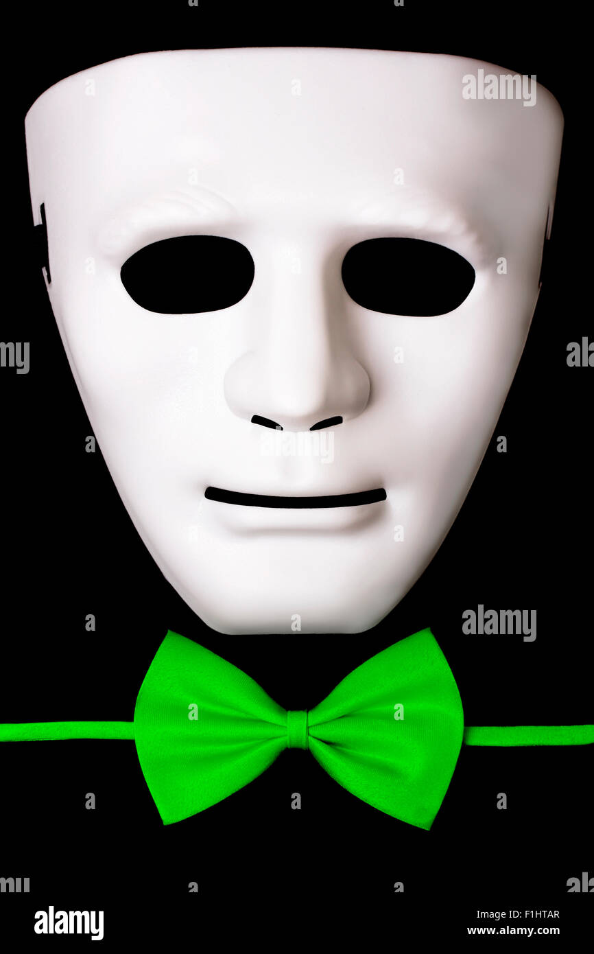 White mask and green bow tie isolated on black background Stock Photo
