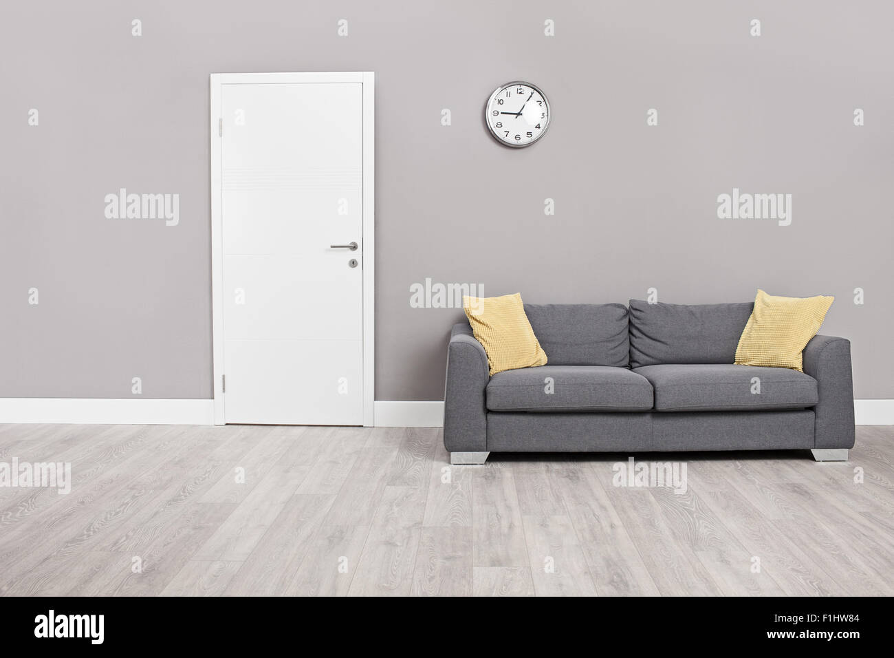 Empty waiting room with a modern gray sofa in front of the door and a